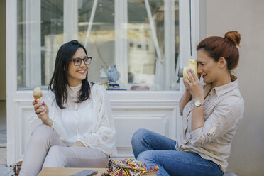 Woman taking picture of happy friend with ice cream - MOMF00181