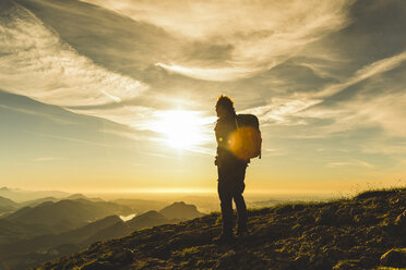 Wanderer steht auf einem Berggipfel und betrachtet die Aussicht - UUF10998