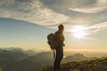 Hiker standing on mountain summit looking at view - UUF11004