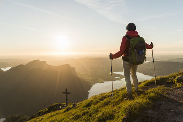 Frau mit Wanderstöcken, die den Sonnenuntergang betrachtet, wandert allein in den Bergen - UUF11033