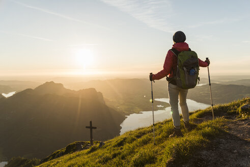 Woman with hiking poles looking at sunset hiking alone in the mountains - UUF11033