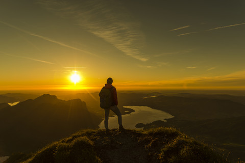 Hiker standing on mountain summit, looking at view at sunset stock photo
