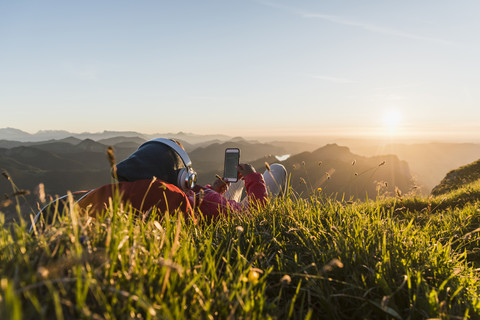 Hiker lying in grass, taking a break and listening music with headphones stock photo
