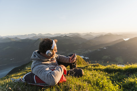 Hiker lying in grass, taking a break and listening music with headphones stock photo