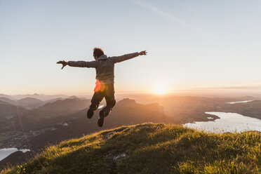 Austria, Salzkammergut, Hiker on mountains summit jumping for joy - UUF11050