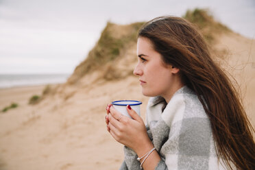 Junge Frau mit einer Tasse heißer Schokolade am Strand - NMSF00127