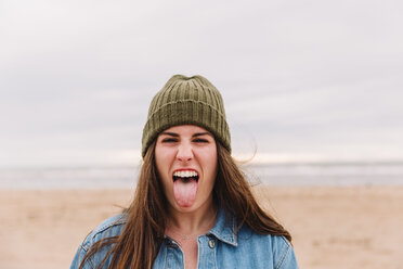 Portrait of woman sticking out tongue on the beach - NMSF00132