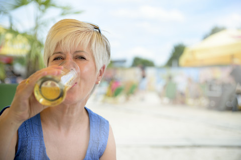 Portrait of senior woman drinking beer at beach bar stock photo