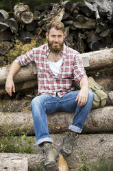 Porträt eines bärtigen Mannes, der auf einem Holzstapel sitzt - MAEF12379