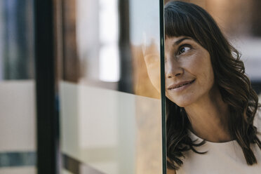 Portrait of a businesswoman looking through glass pane - KNSF01988