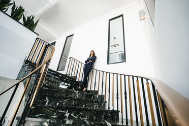 Successful businesswoman standing on staircase - KNSF02015