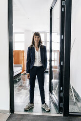 Geschäftsfrau in Turnschuhen, stehend in offener Tür - KNSF02021