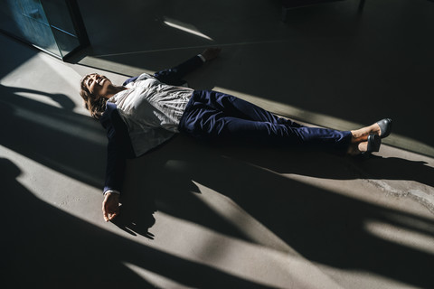 Geschäftsfrau auf dem Boden liegend im Büro, lizenzfreies Stockfoto