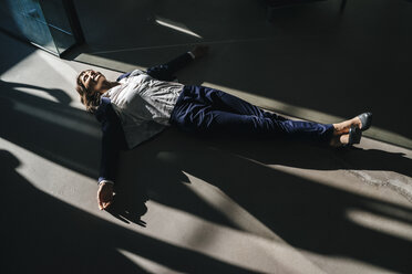 Businesswoman lying on floor in office - KNSF02032