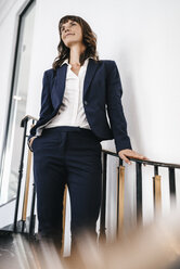 Successful businesswoman standing on staircase - KNSF02034