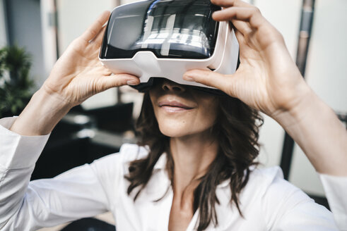 Businesswoman using VR goggles in office - KNSF02041