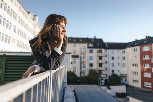 Businesswoman staanding on balcony enjoying the sunshine - KNSF02048