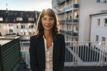 Businesswoman staanding on balcony enjoying the sunshine - KNSF02049