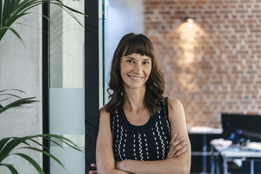 Businesswoman standing in office with arms crossed - KNSF02053