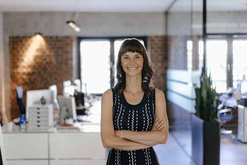 Businesswoman standing in office with arms crossed - KNSF02055