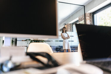 Businesswoman standing in office with arms crossed - KNSF02075