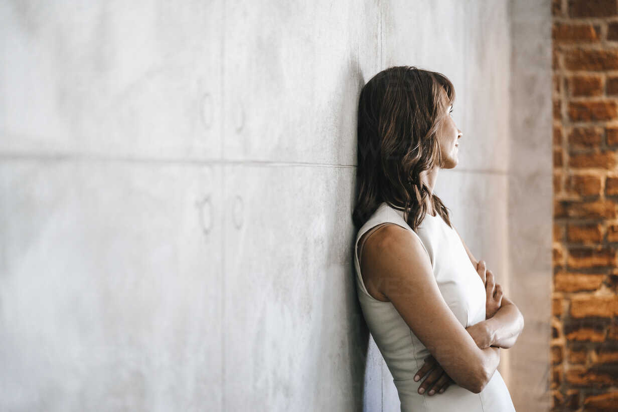 A woman standing behind a wall with her arms stretched out photo