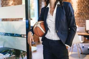 Businesswoman holding basket ball in office - KNSF02099