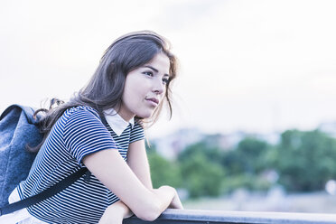 Pensive young woman with backpack leaning on railing - UUF11054