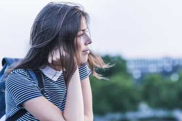 Pensive young woman with backpack leaning on railing - UUF11056