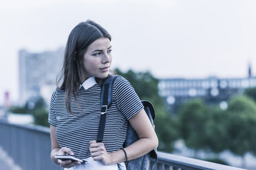 Porträt einer jungen Frau mit Rucksack und Mobiltelefon - UUF11062