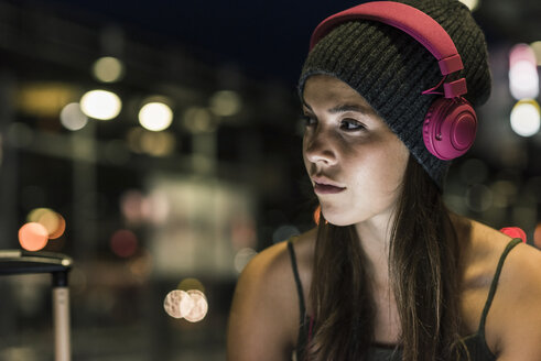 Portrait of young woman with headphones at night - UUF11068