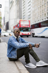 USA, New York City, Manhattan, stilvoller Mann sitzt auf Bordsteinkante - MAUF01157