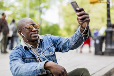 Portrait of smiling man wearing mirrored sunglasses taking selfie with smartphone - MAUF01158