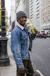 USA, New York City, Manhattan, Porträt eines lächelnden Mannes mit Flasche - MAUF01165