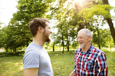 Älterer Vater und sein erwachsener Sohn lachen zusammen in einem Park - HAPF01862