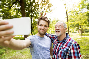 Portrait of senior father and his adult son taking selfie in a park - HAPF01866