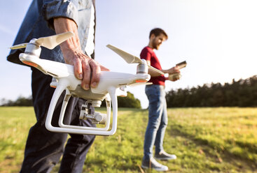 Senior father and his adult son with drone on a meadow - HAPF01874