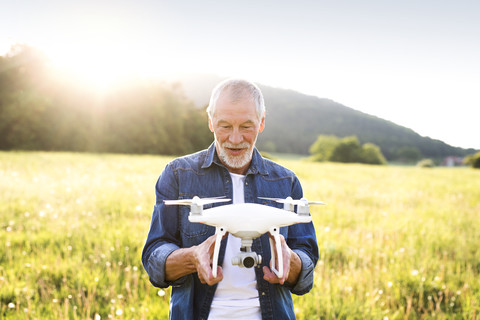 Porträt eines älteren Mannes mit Drohne auf einer Wiese, lizenzfreies Stockfoto