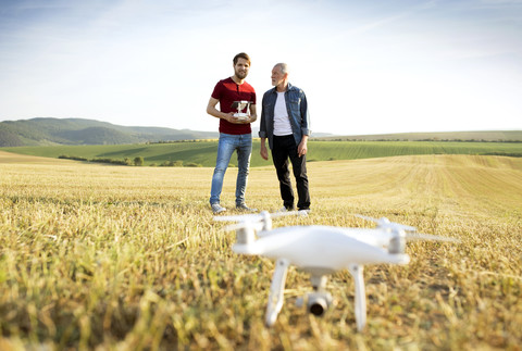 Älterer Vater und sein erwachsener Sohn mit Drohne auf einem Feld, lizenzfreies Stockfoto
