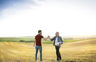 Älterer Vater und sein erwachsener Sohn mit Drohne auf einem Feld - HAPF01881