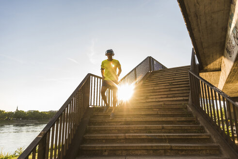 Junger Sportler beim Joggen über eine Treppe in der Stadt - UUF11125