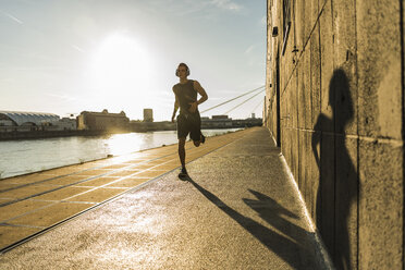 Junger Sportler beim Joggen in der Stadt am Fluss - UUF11134