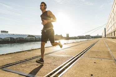 Junger Sportler beim Joggen in der Stadt am Fluss - UUF11136