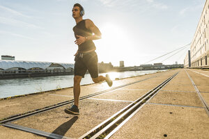 Junger Sportler beim Joggen in der Stadt am Fluss - UUF11136