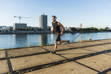 Young athlete jogging in the city at the river - UUF11137