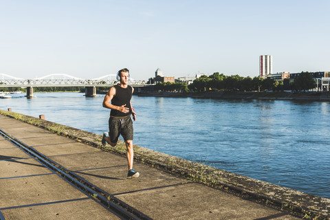 Junger Sportler beim Joggen in der Stadt am Fluss, lizenzfreies Stockfoto