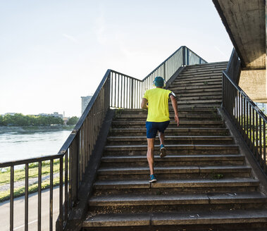 Junger Sportler beim Joggen über eine Treppe in der Stadt - UUF11155