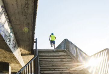 Junger Sportler beim Joggen über eine Treppe in der Stadt - UUF11156