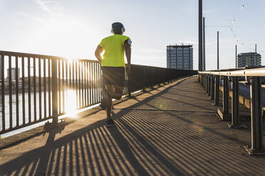 Junger Sportler joggt auf einer Brücke in der Stadt - UUF11157