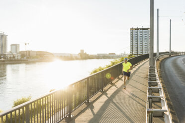 Junger Sportler joggt auf einer Brücke in der Stadt - UUF11159